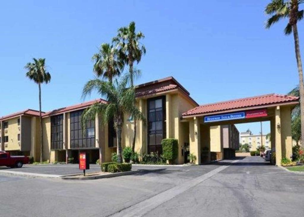 a building with palm trees in front of a street at California Inn and Suites Bakersfield in Bakersfield
