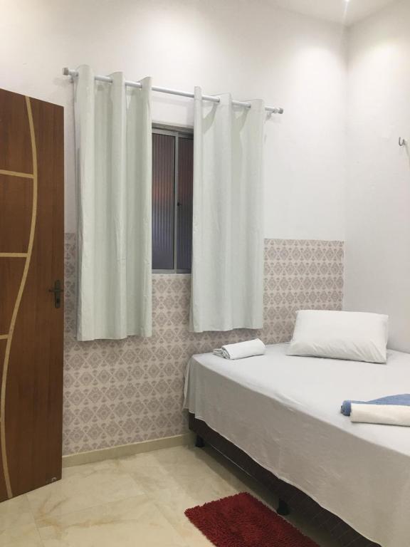 a bedroom with two beds and a window with curtains at Rosana House Bem estar em Barreirinhas Ideal para 5 pessoas in Barreirinhas