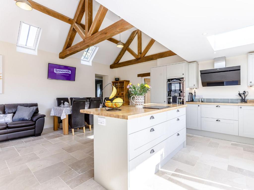 a kitchen with white cabinets and a living room at The Old Dairy in Shipton under Wychwood