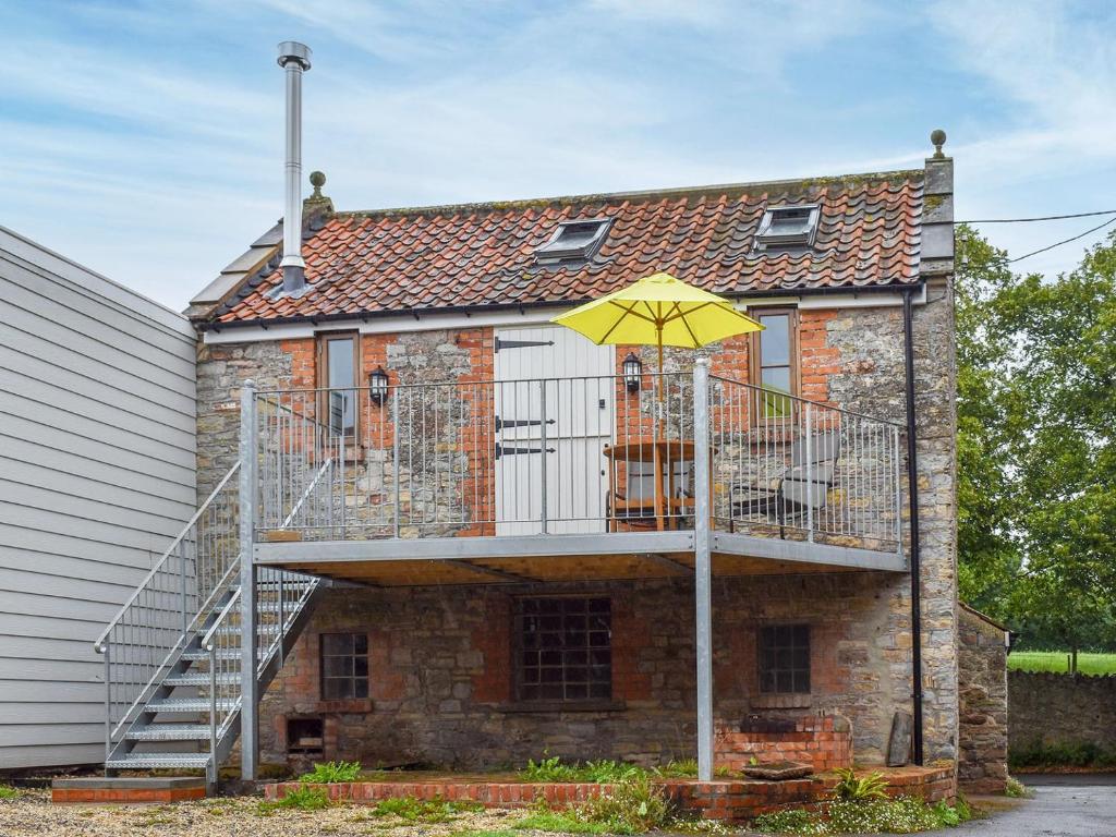 uma casa com uma escada e um guarda-chuva amarelo em The Chaff House em Wookey
