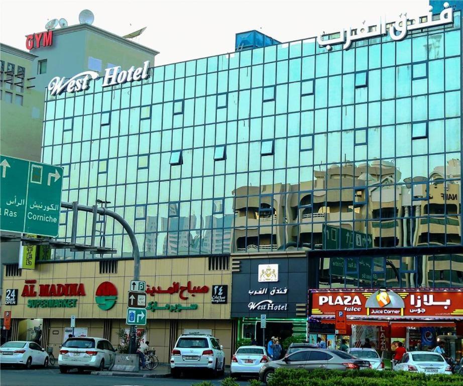 un gran edificio de cristal con coches estacionados frente a él en West Hotel en Dubái