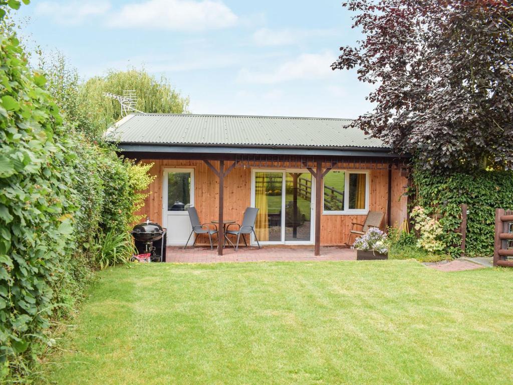een klein huis met een patio en een tuin bij The Lodge At Forbury Cottage in Kimbolton