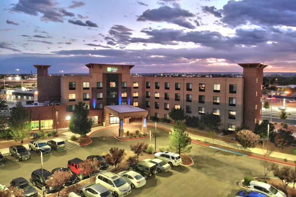 ein großes Gebäude mit Autos auf einem Parkplatz in der Unterkunft Holiday Inn Express & Suites Albuquerque Historic Old Town, an IHG Hotel in Albuquerque