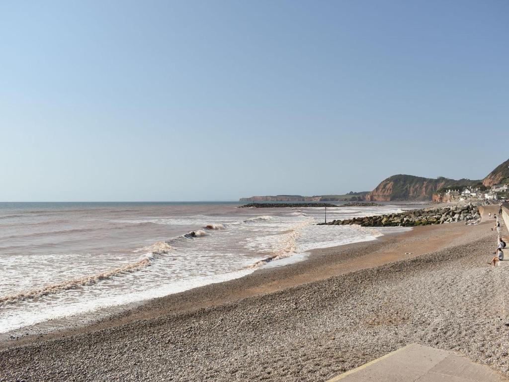 a beach with a group of people walking on the sand at The Costal Hideaway in Sidmouth