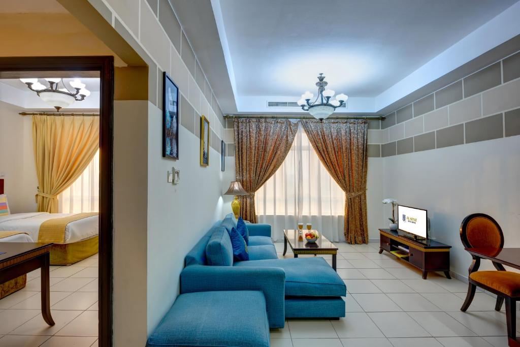 a hotel room with a blue couch and a bed at Al Hayat Hotel Apartments in Sharjah