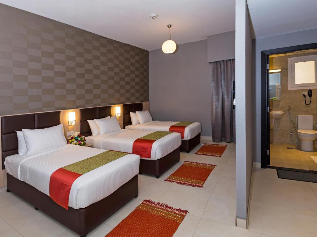 a hotel room with two beds and a bathroom at Florida Square Hotel (Previously known Flora Square Hotel) in Dubai