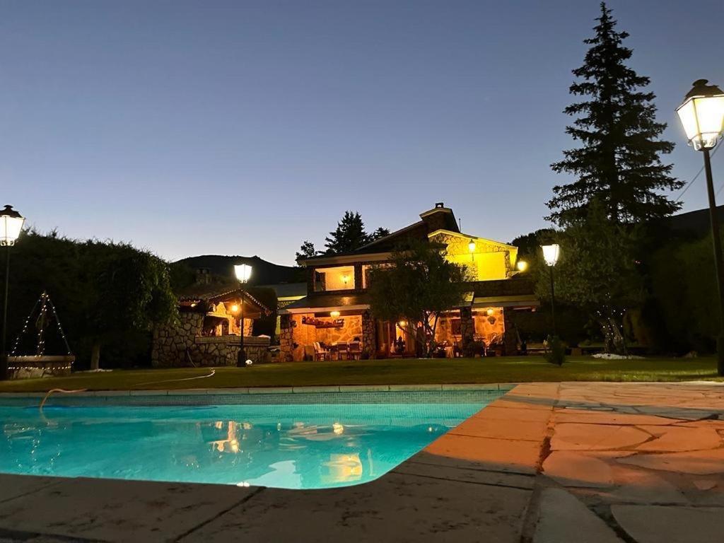 Bustarviejo的住宿－Casa Rural LOS TINES，房屋前有游泳池的房子