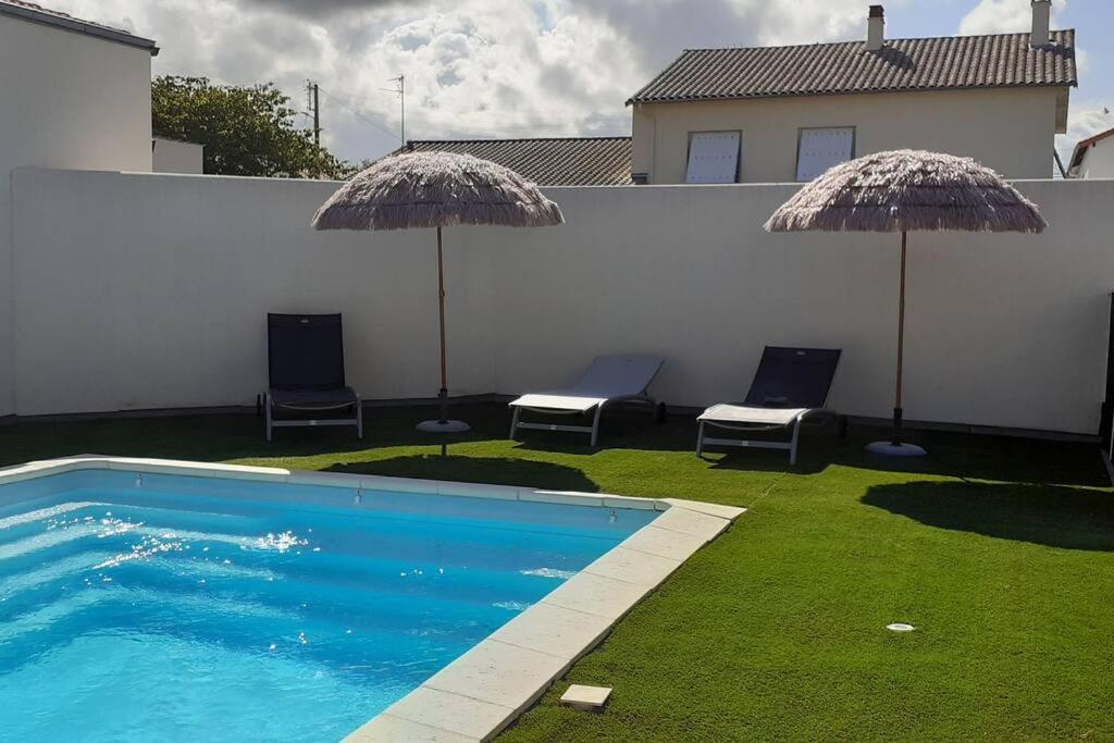 - une piscine avec 2 chaises longues et 2 parasols dans l'établissement Villa Louna, à Châtelaillon-Plage