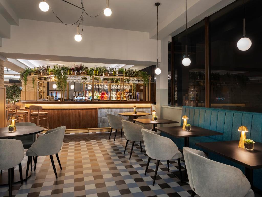 a restaurant with tables and chairs and a bar at Leonardo Royal Hotel Birmingham in Birmingham