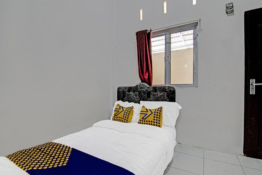 a bedroom with a bed with yellow and blue pillows at SPOT ON 91699 Homestay Hj Lela Syariah in Pekanbaru