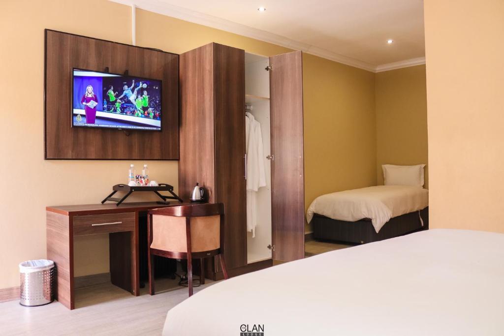ein Hotelzimmer mit einem Bett und einem TV an der Wand in der Unterkunft THE CLAN LODGE in Mohlanapeng