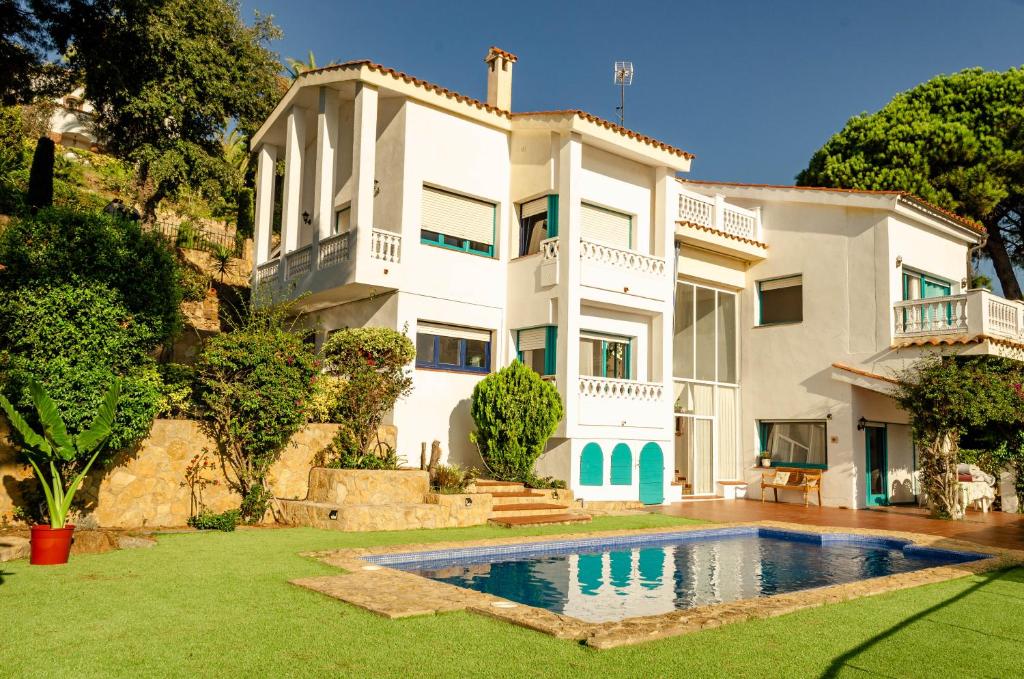 a white house with a swimming pool in front of it at ~Villa El Riu del Cel~Increíbles vistas al mar in Lloret de Mar