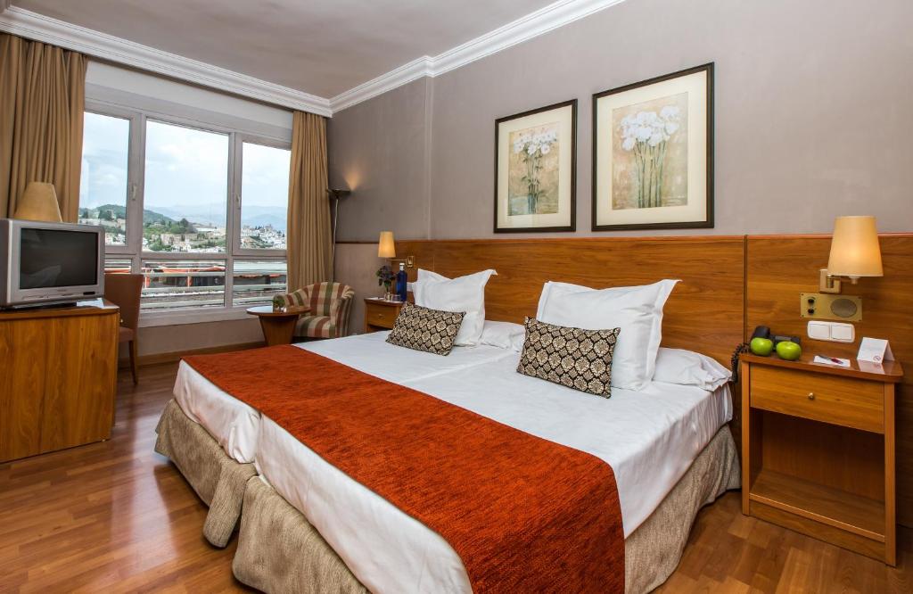 Habitación de hotel con cama y TV en Leonardo Hotel Granada, en Granada