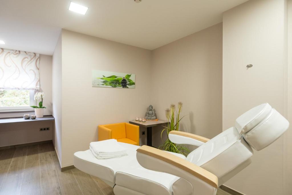 a living room with a white chair and a table at Hotel Haus Tiefenbach in Bullange