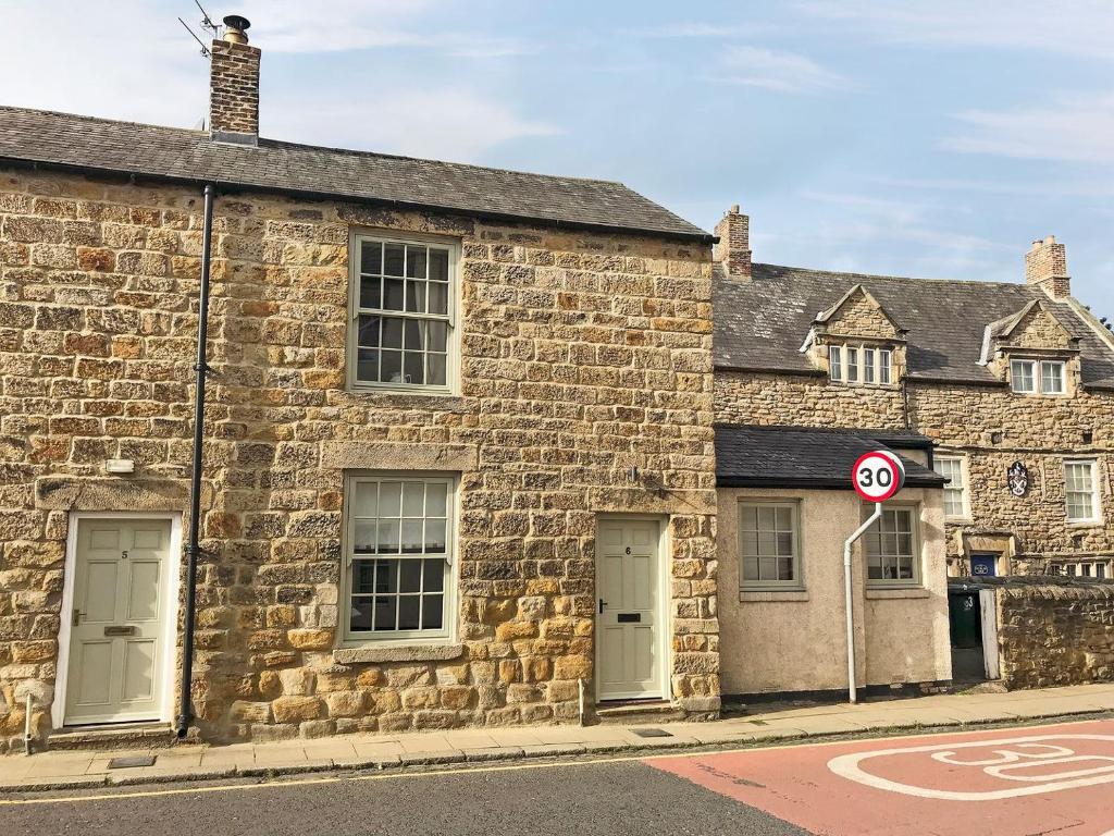 an old stone building on a street with a no parking sign at Gadir in Hexham