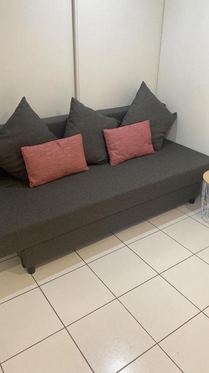 un divano grigio con due cuscini rossi sopra di Studio - Carré de Soie Vaulx en Velin a Vaulx-en-Velin