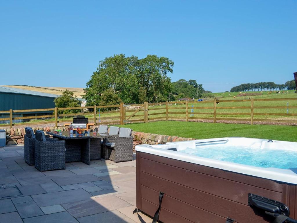a hot tub on a patio with a table and chairs at Auchen Ladder in Amisfield Town