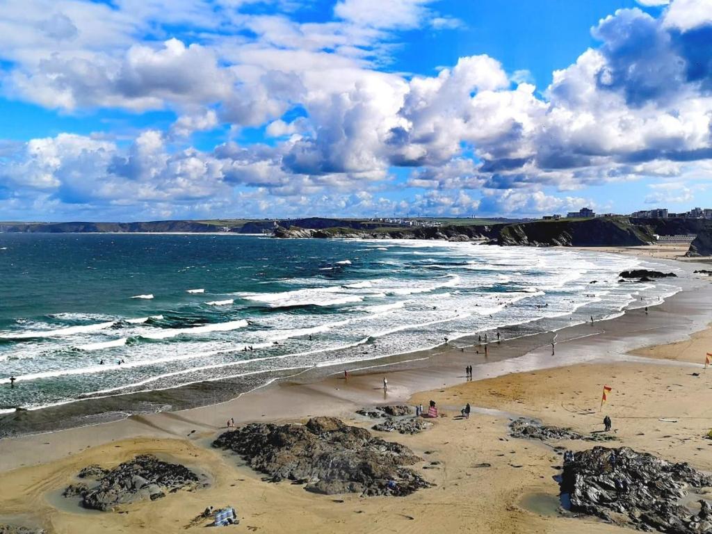 a beach with people on the sand and the ocean at The Penthouse - Clearview in Newquay