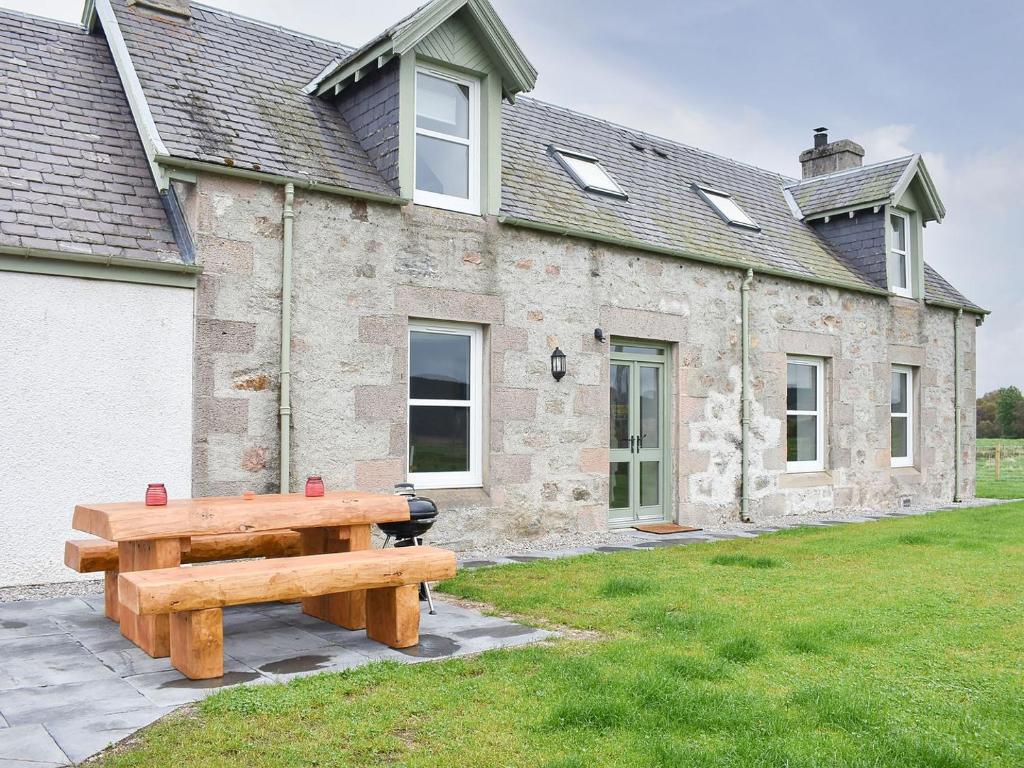 a wooden bench sitting in front of a building at 1 Dalbuaick Farm Cottage in Carrbridge