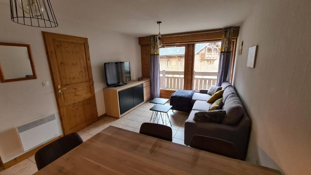 sala de estar con sofá, mesa y TV en Apprt 41m2 6 pers avec 2 chambres, 1 coin montage avec garage en Les Deux Alpes