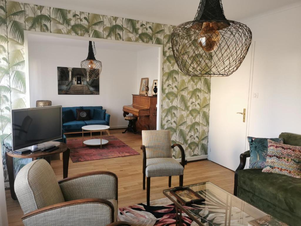 uma sala de estar com um sofá e uma televisão em La Maison de Lucie - grande maison idéale en famille ou entre amis - jardin - parking gratuit em Sélestat