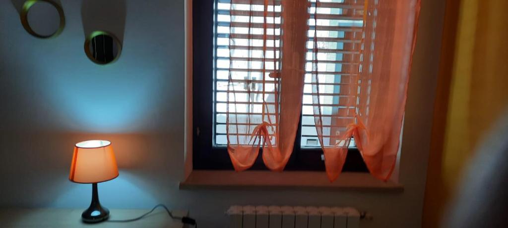 Le Gemme del Centro Storico في بوتنزا: نافذة بها ستارة برتقالية ومصباح
