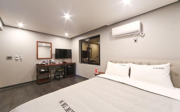 a bedroom with a bed and a desk with a television at Tongyeong Mu in Tongyeong