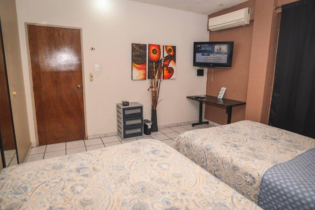 1 dormitorio con 2 camas, escritorio y puerta en Departamento D centrico 2 camas Tv Ac wifi cocina parking, en Ciudad Valles