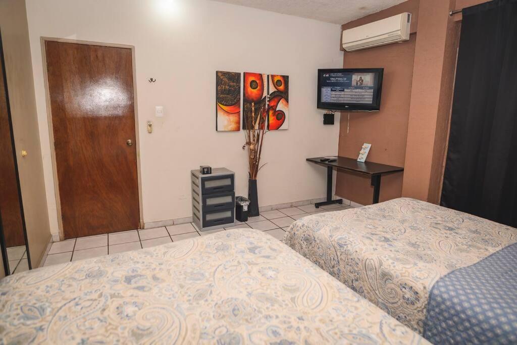 a bedroom with two beds and a desk and a door at Departamento D centrico 2 camas Tv Ac wifi cocina parking in Ciudad Valles