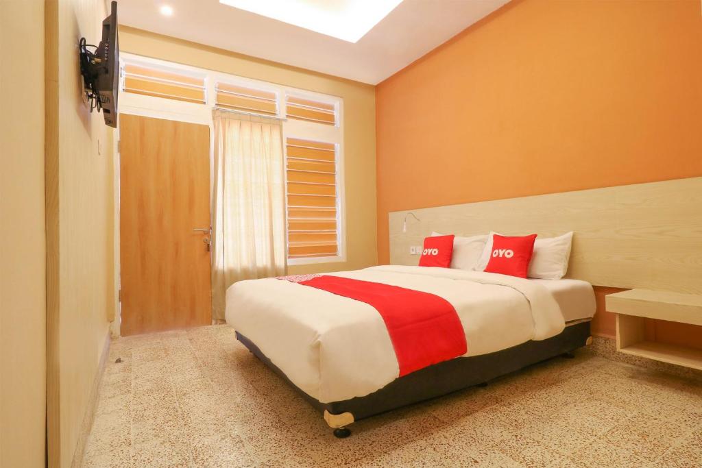 una camera da letto con un grande letto con cuscini rossi di OYO 1384 Pulau Bali Hotel a Denpasar