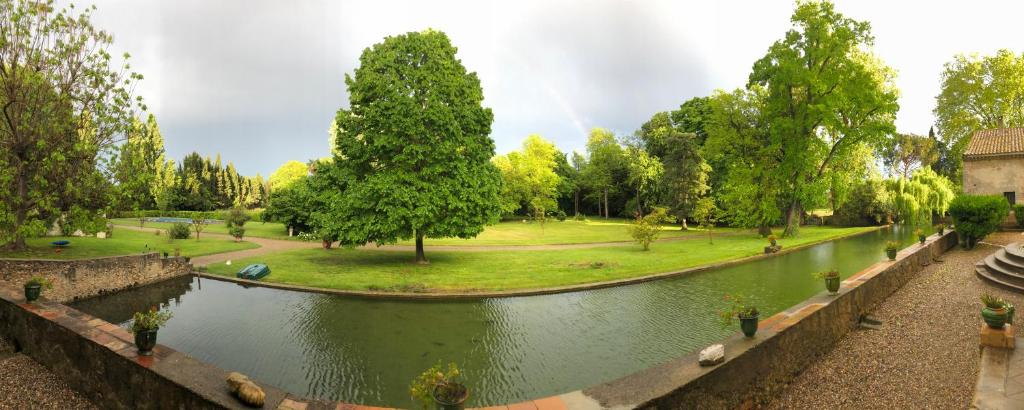 un estanque en un parque con árboles y un campo en Gîte Superbe L'Ecurie XIXème, en Sallèles-dʼAude