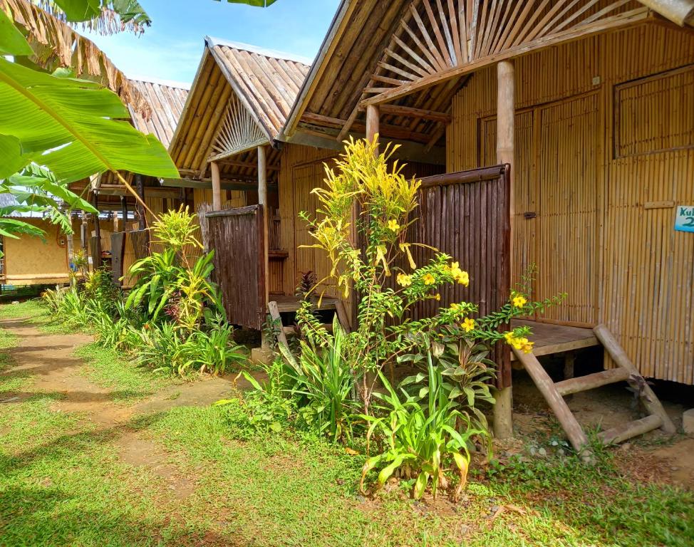 ein Holzgebäude mit einer Bank davor in der Unterkunft Banana Grove El Nido in El Nido