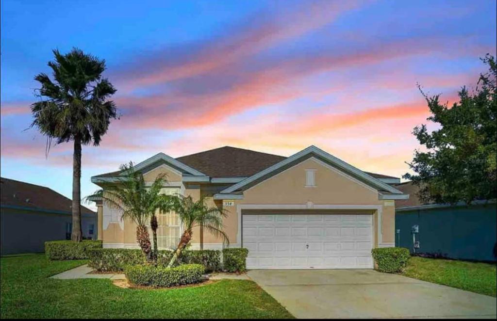a house with a garage and a palm tree at Chic villa 4 Bedroom 3 Bath with pool & game room in Davenport