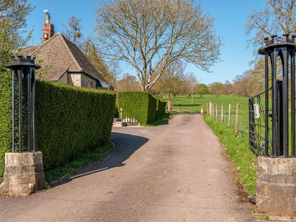 una carretera que conduce a una casa con una valla de protección en The Gatehouse Cottage, en Wells