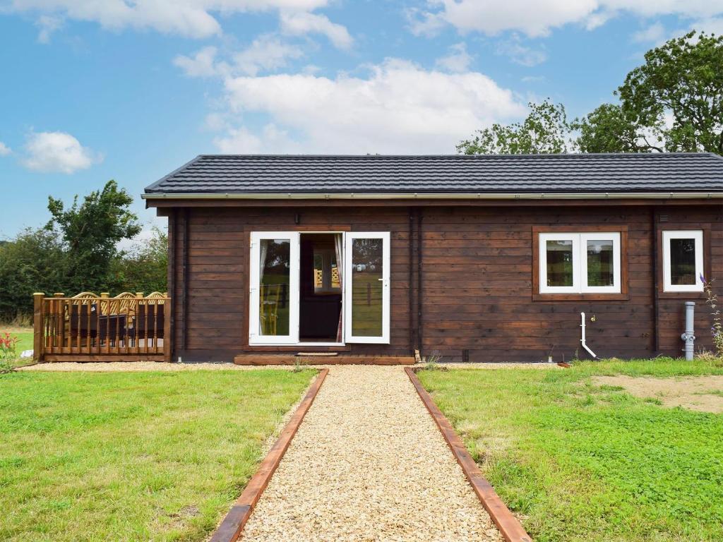 una pequeña casa de madera con un patio de césped en Raynards Retreat - Uk33401 en Hungerton