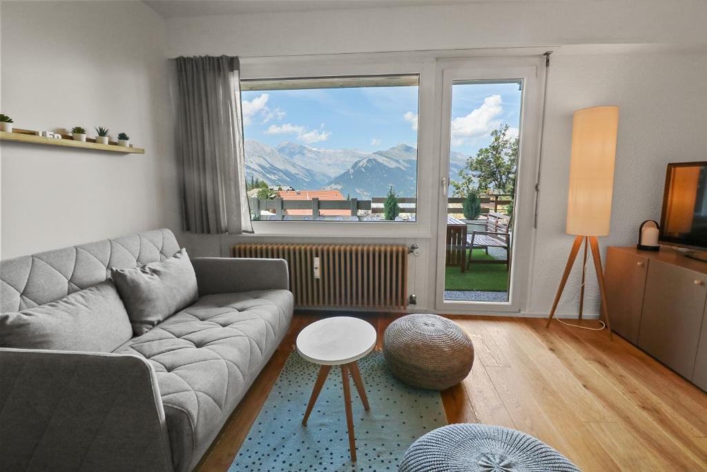 un soggiorno con divano e una grande finestra di Superbe appartement avec piscine a Nendaz