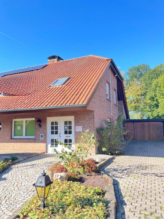 a brick house with a red roof and a driveway at Ferienwohnung Zeitlos in Bad Bentheim