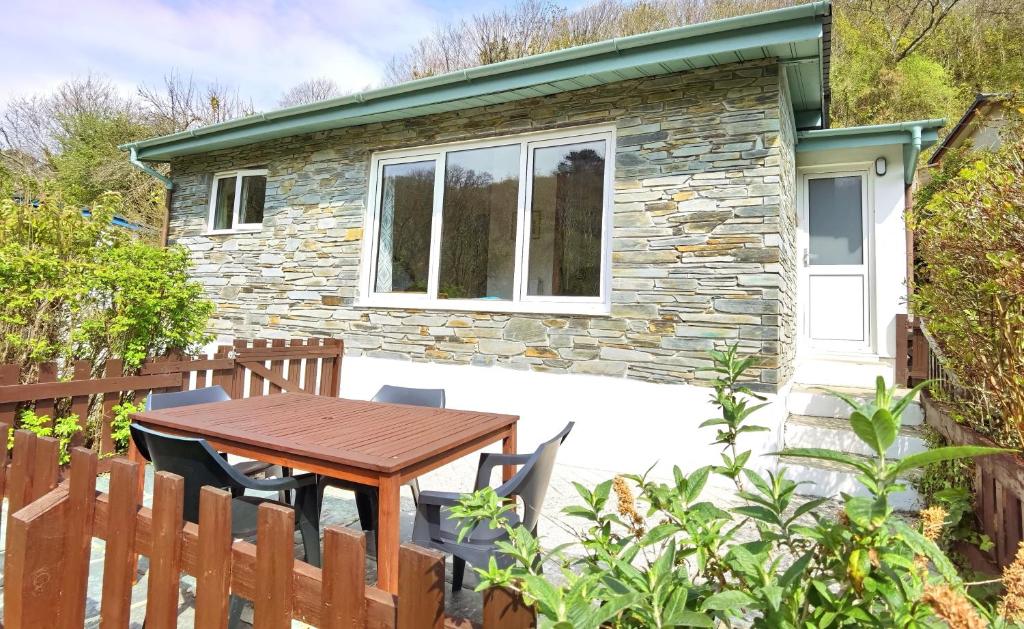 a stone cottage with a wooden table in front of it at Kiberick Cottage at Crackington Haven, near Bude and Boscastle, Cornwall in Bude