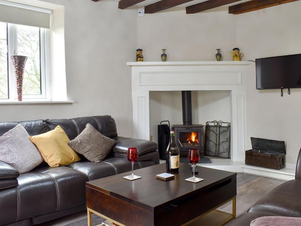 a living room with a leather couch and a fireplace at Dewy Lane Farm House in Tansley