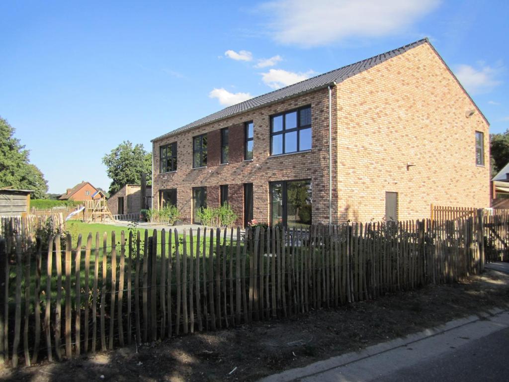 ein Backsteingebäude mit einem Zaun davor in der Unterkunft De Hoog Velden 11 in Neerpelt