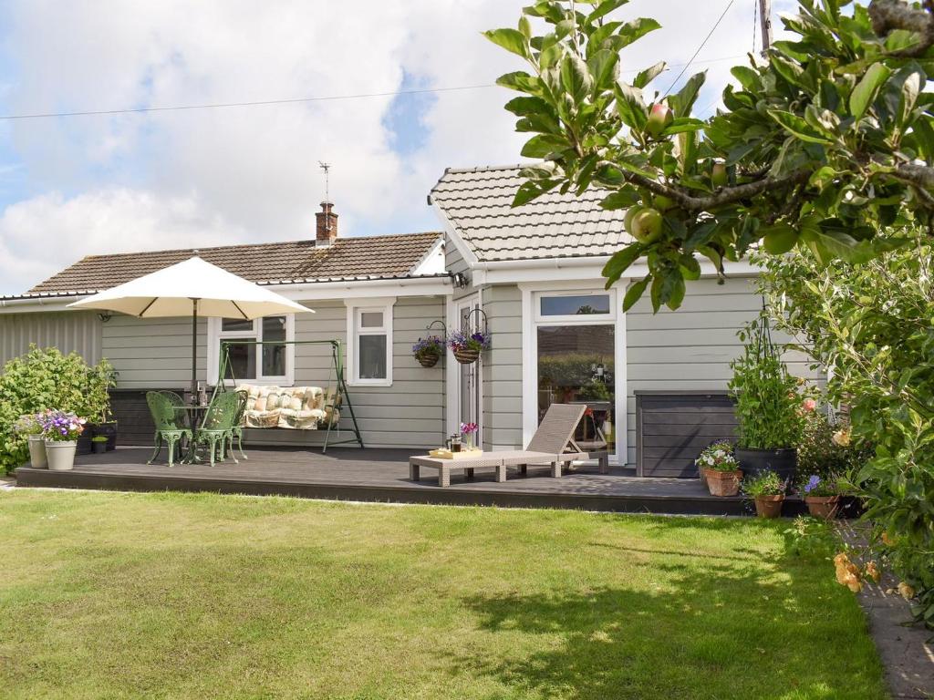 a house with a patio with chairs and an umbrella at Lawn Vista Cabin in Barnstaple