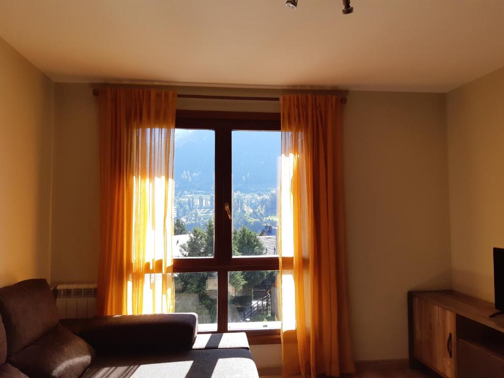 una sala de estar con una gran ventana con cortinas de color naranja en Apartamento familiar con vistas y garage La Portiecha, en Sallent de Gállego