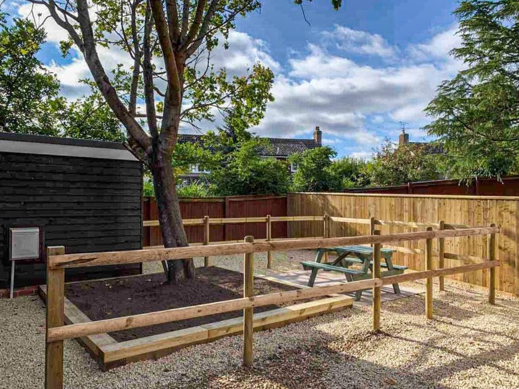 a wooden bench next to a tree with a fence at The Oaks - Uk33998 in Child Okeford