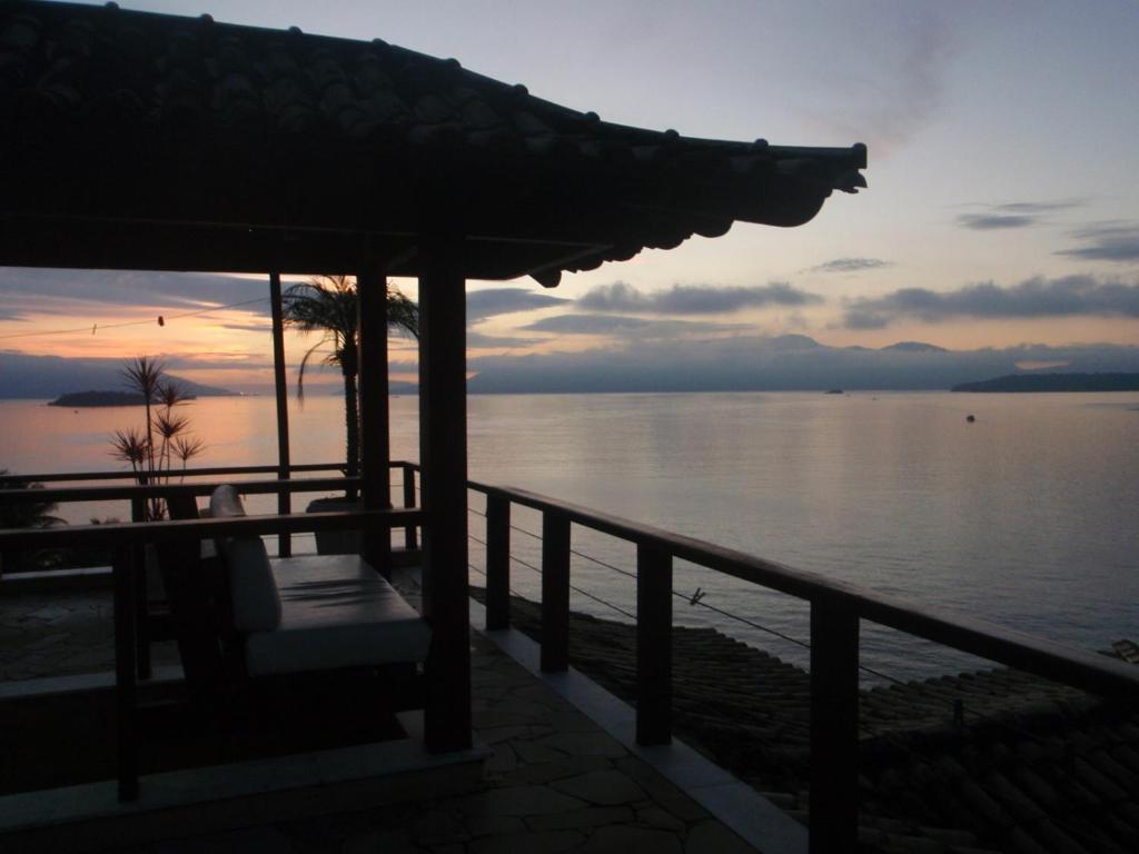einen Sonnenuntergang über dem Wasser mit einer Bank auf einem Pier in der Unterkunft Pousada Casa Atlântica in Angra dos Reis