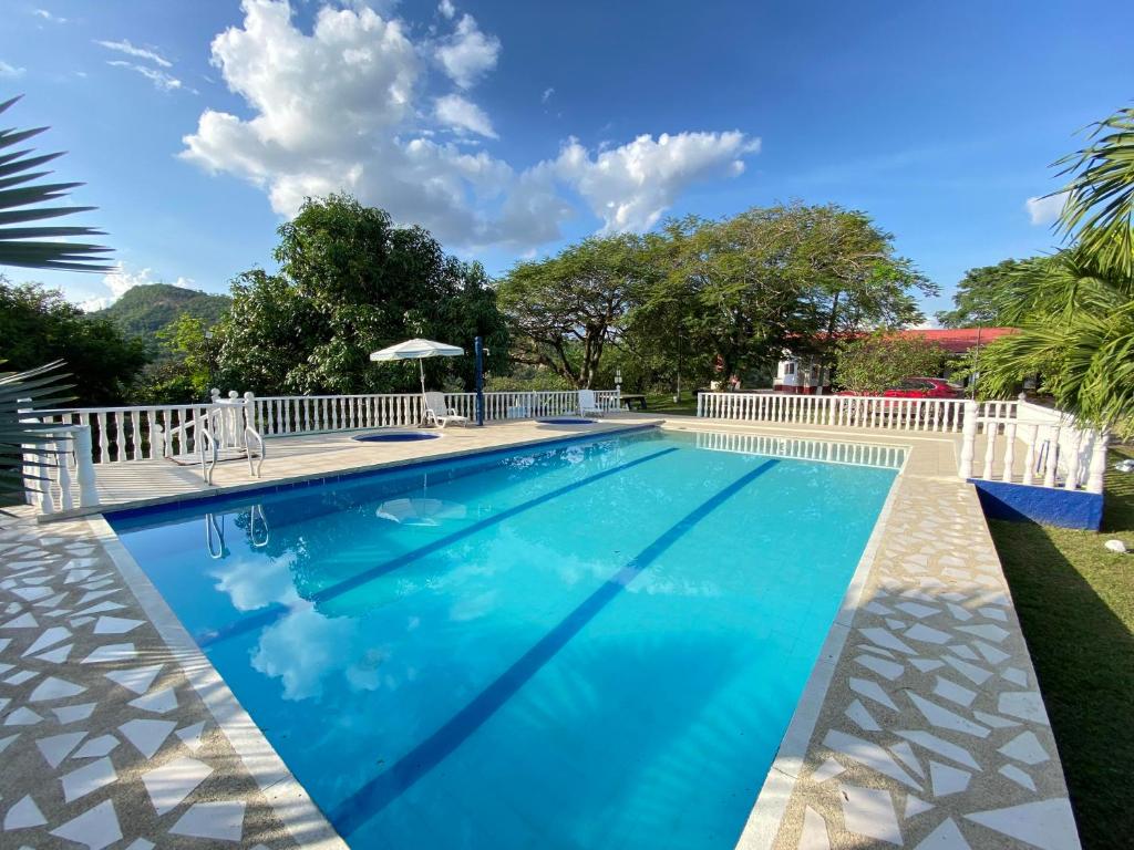 a swimming pool with a white fence and blue water at Finca Villa Sofía Campestre con piscina in Anapoima