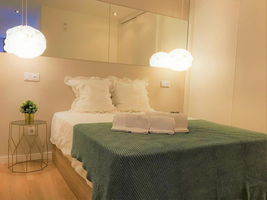 a bedroom with a bed with a green table and two lights at Apartamento Veneza Portuguesa - Coração de Aveiro in Aveiro