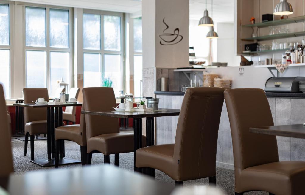 ein Restaurant mit Tischen und Stühlen und eine Küche in der Unterkunft Stadt-gut-Hotel Großer Kurfürst in Emden