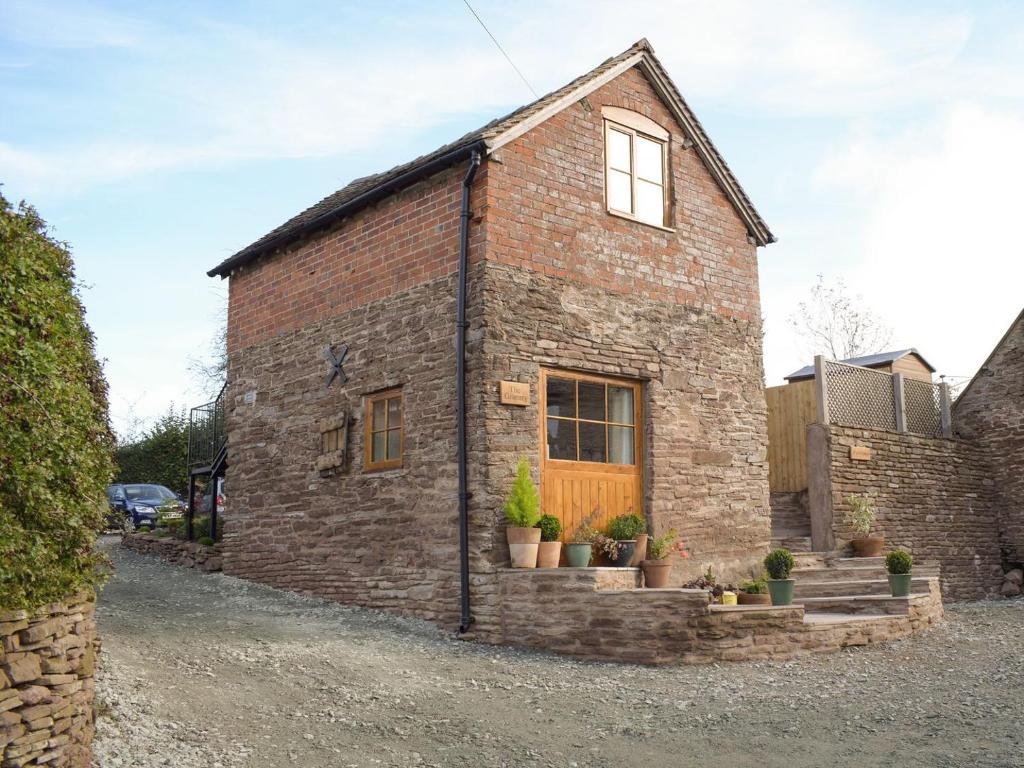 a brick house with a wooden door and potted plants at The Granary in Clee Saint Margaret