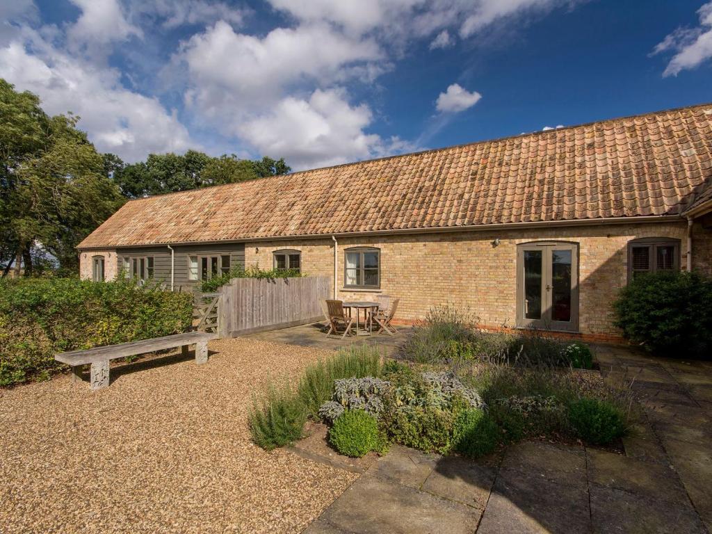 a brick house with a bench in front of it at Alice Cottage in Thurning