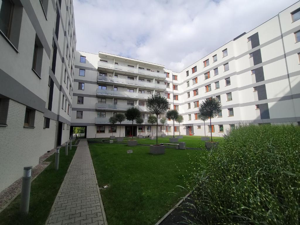 a large white building with a green lawn in front of it at Fajny apartament z parkingiem, obok metra. in Warsaw